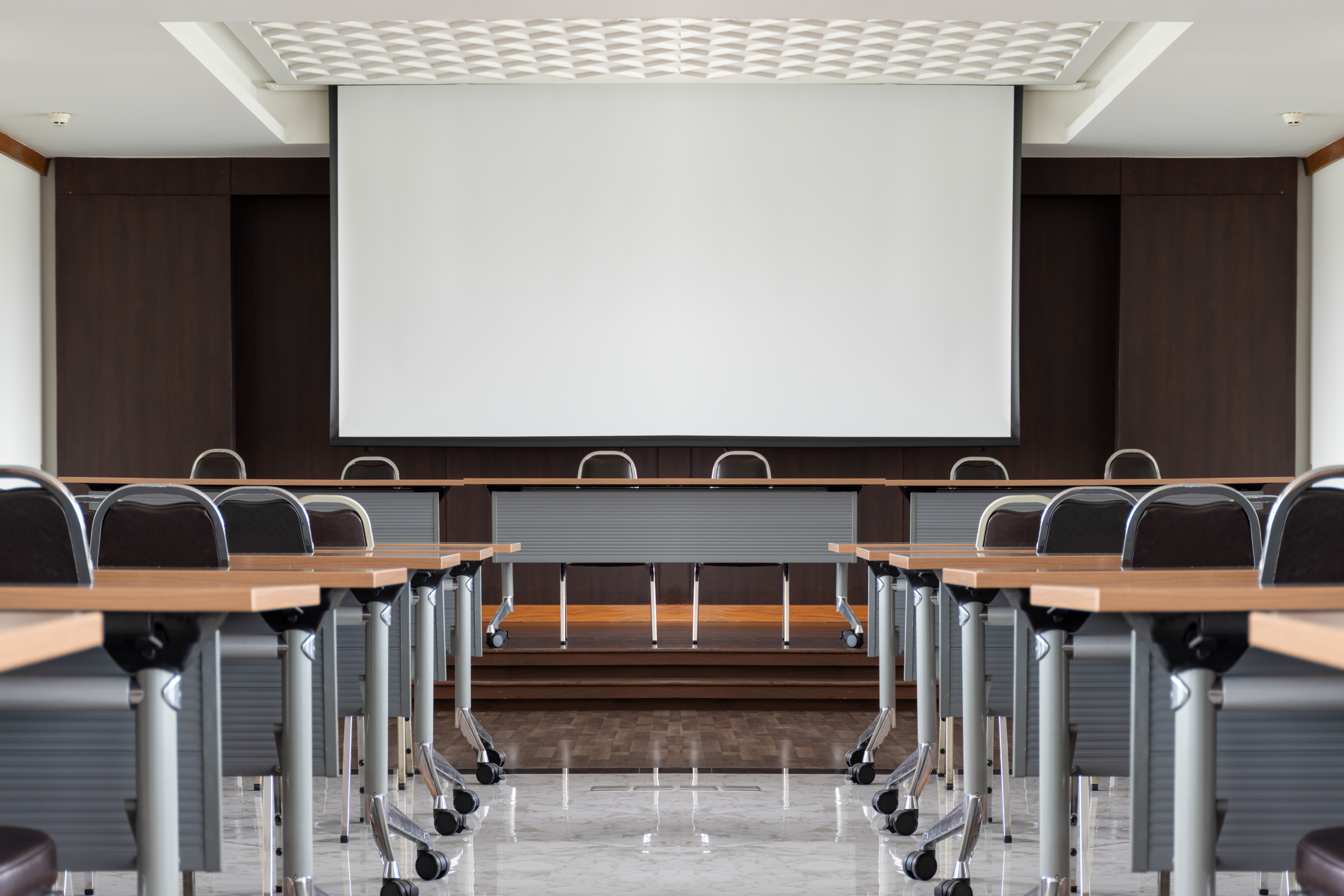 Seminar room with a speaker table in the middle of the stage and whitescreen background