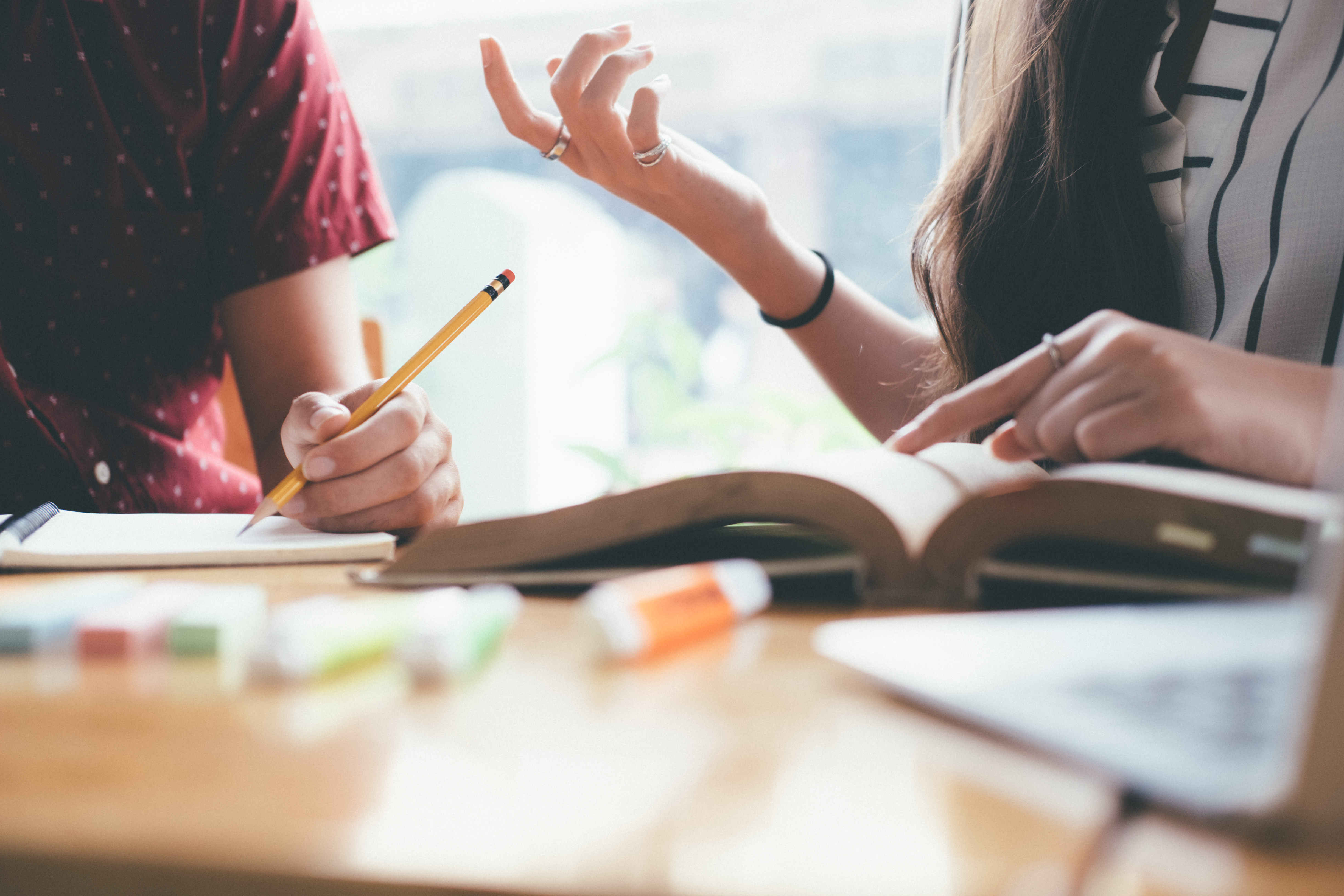 Young woman and man studying for a test or an exam. Tutor books with friends. Young students campus helps friend catching up and learning. People, learning, education and school concept.