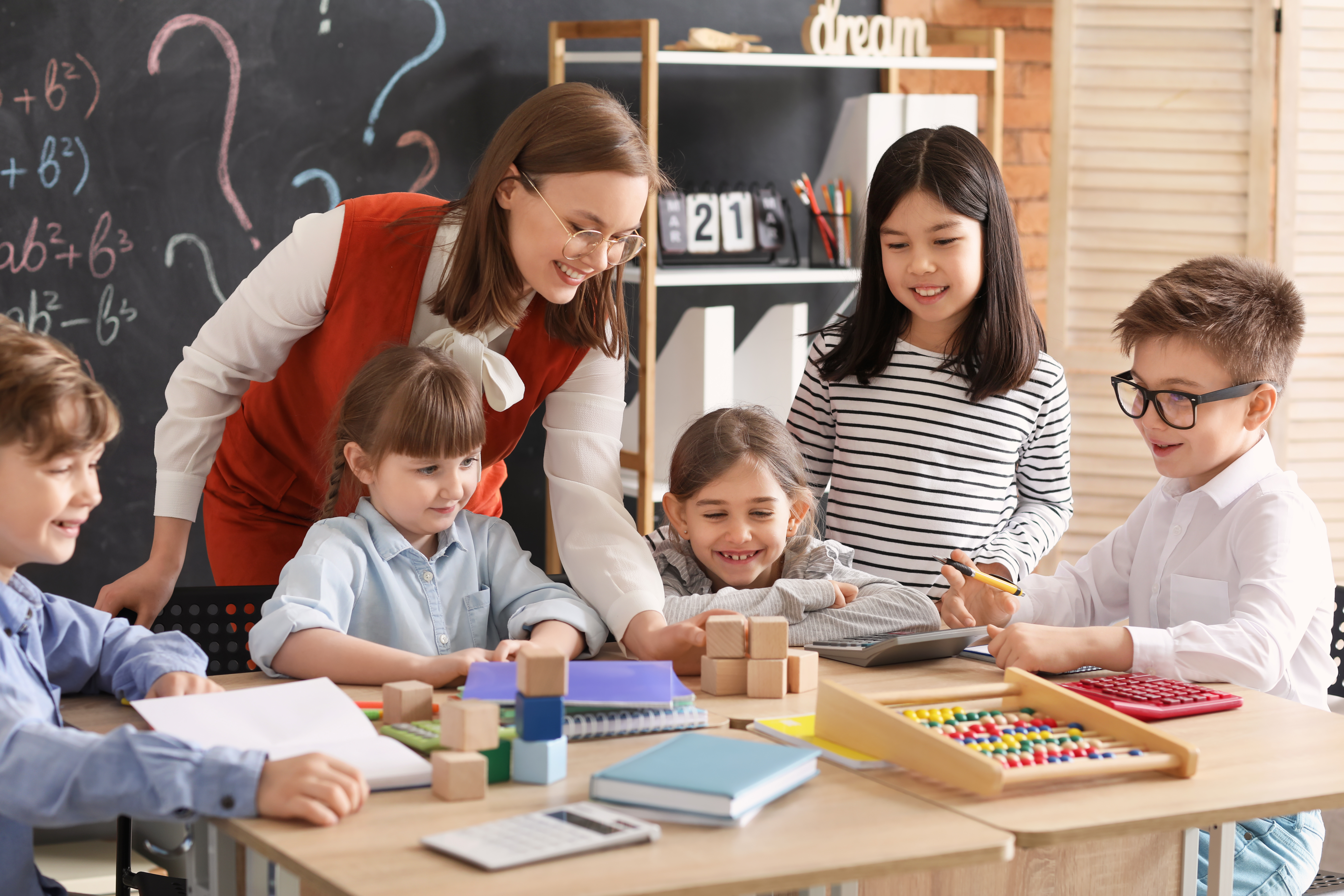 Children with math teacher during lesson in classroom