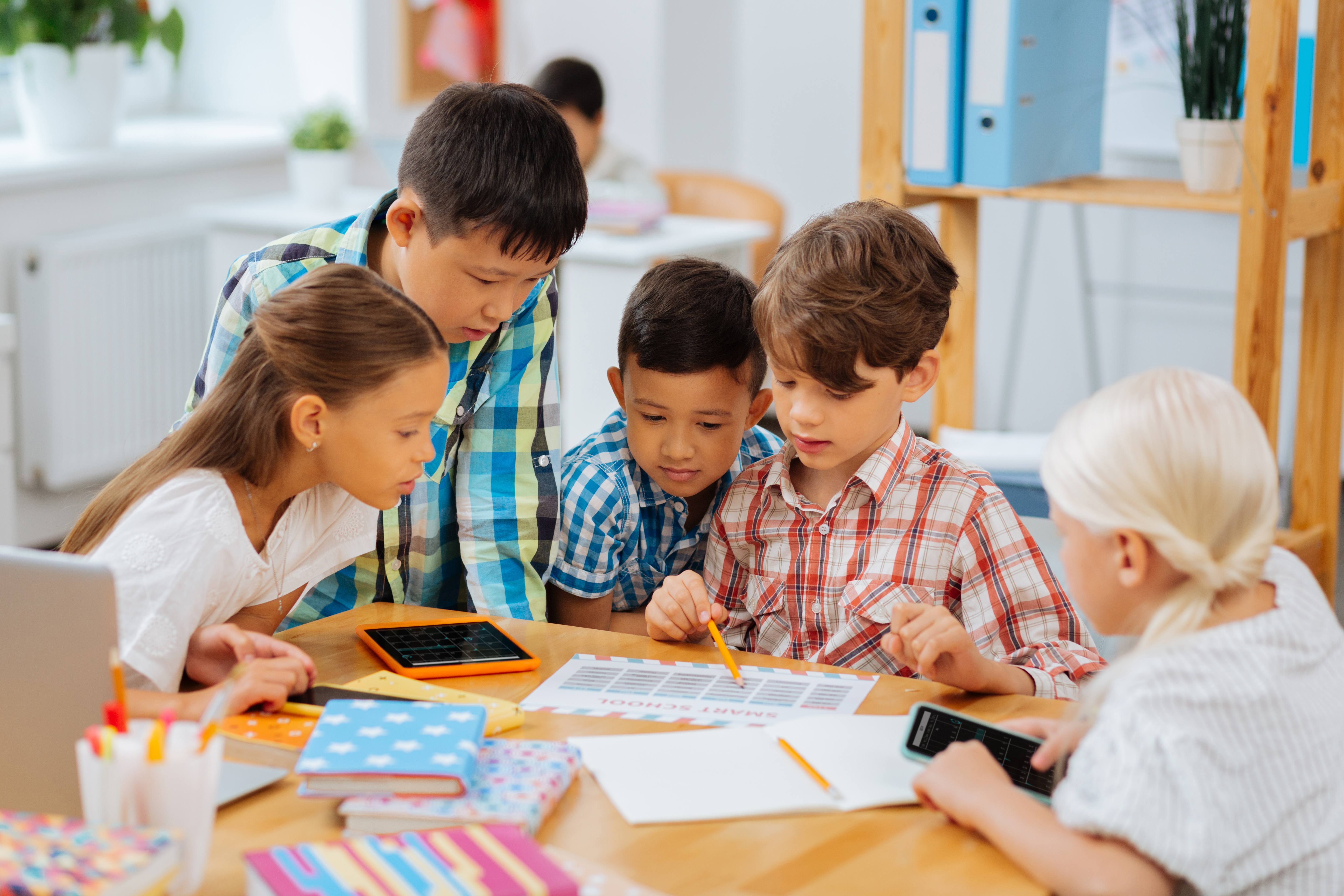 Friendship. Cute sweet company of classmates sitting in a classroom while doing homework