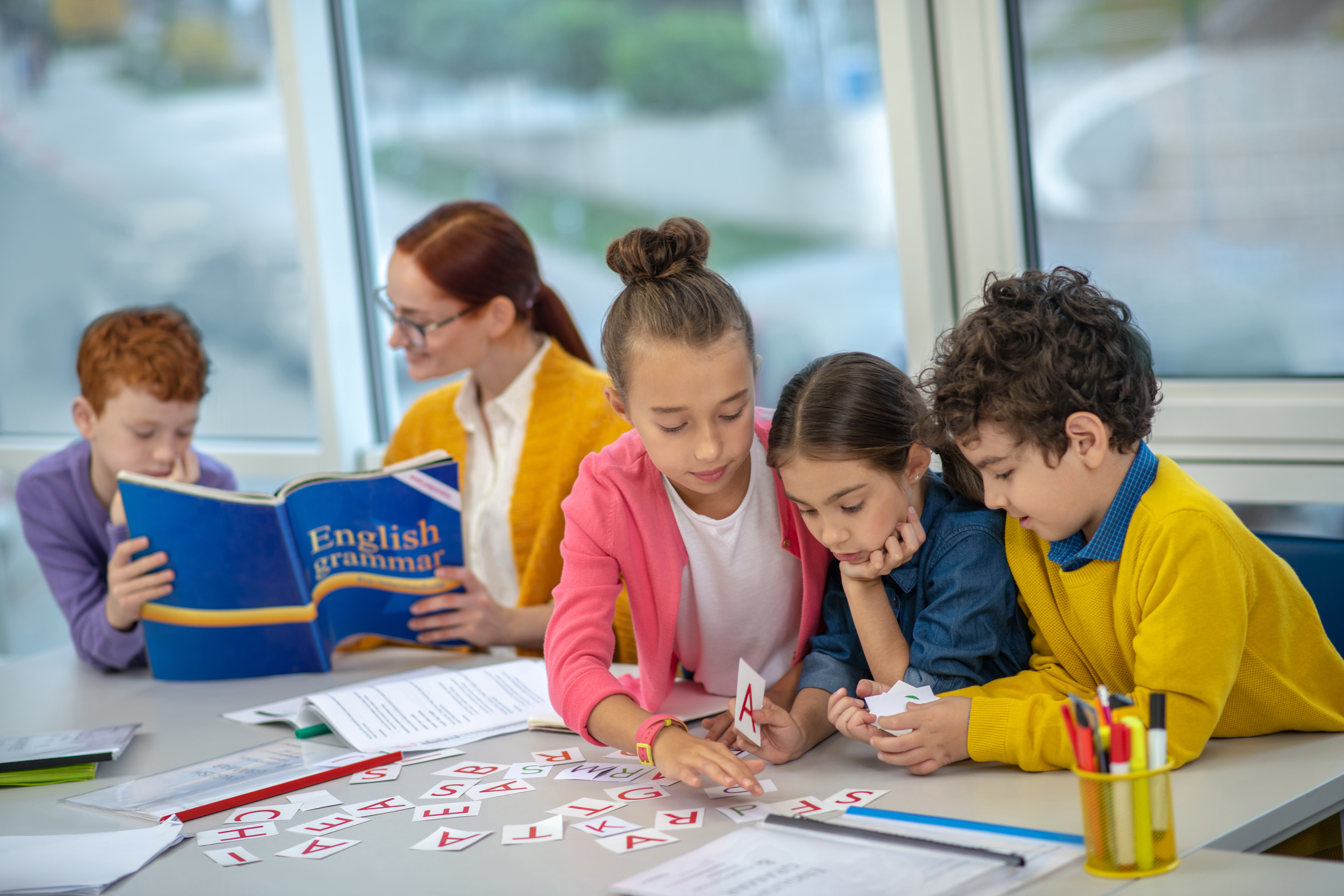 Learning English. Concentrated children learning English grammar at school