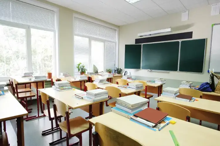 Bright classroom with student desks, a chalkboard, and a presentation display.