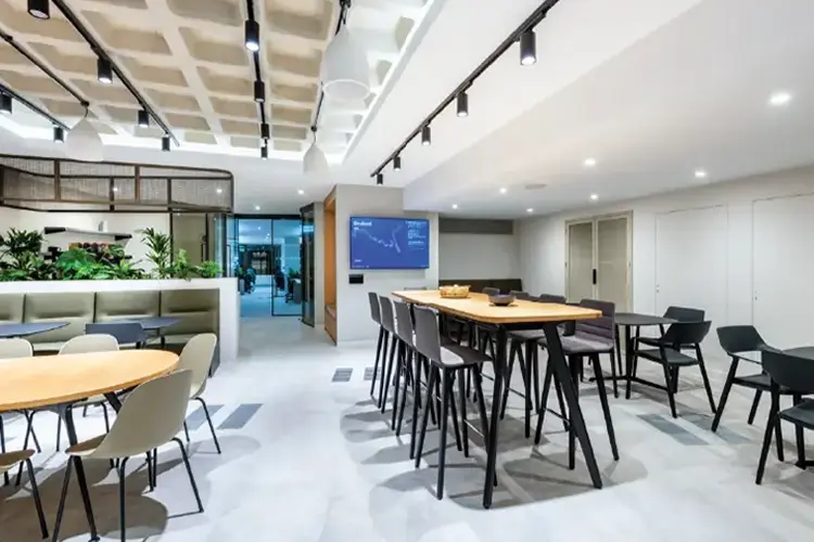 Open shared touchdown workspace with communal tables and a collaboration display.